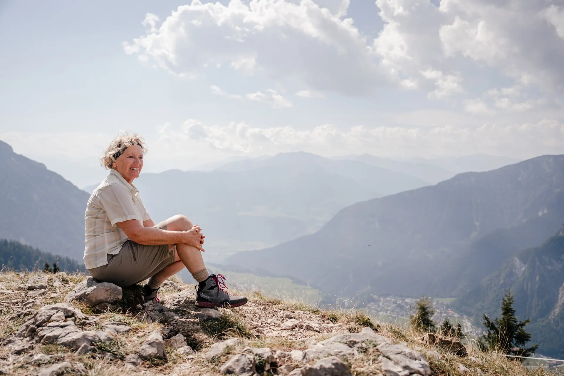 Eine ältere Dame sitzt zufrieden auf einem Felsplateau | © DAV / Marisa Koch